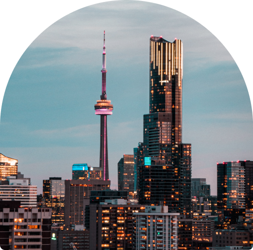 View of the Toronto skyline at dusk, the CN tower illuminated in purple and orange.